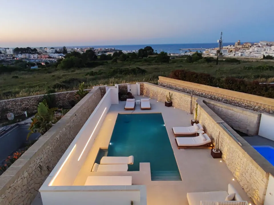 Villa Skyline's pool at dusk, with Otranto's old town and the sea beyond