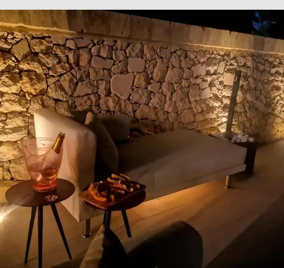 Lit lounge by the natural stone wall in the evening